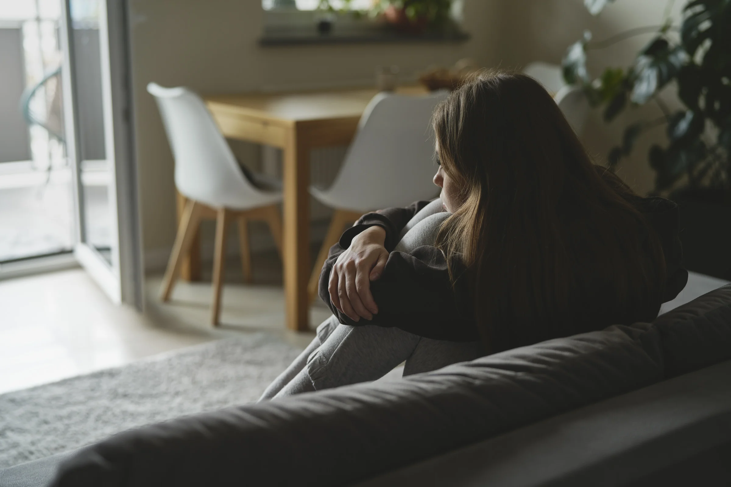 Unterstützung Depression – ein Mädchen sitzt starrend auf dem Sofa